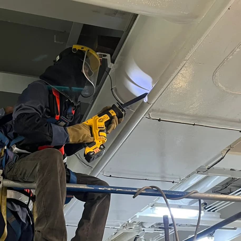 A reciprocating saw taken to the existing deckhead pipework, worked from the boards of the top tier.
